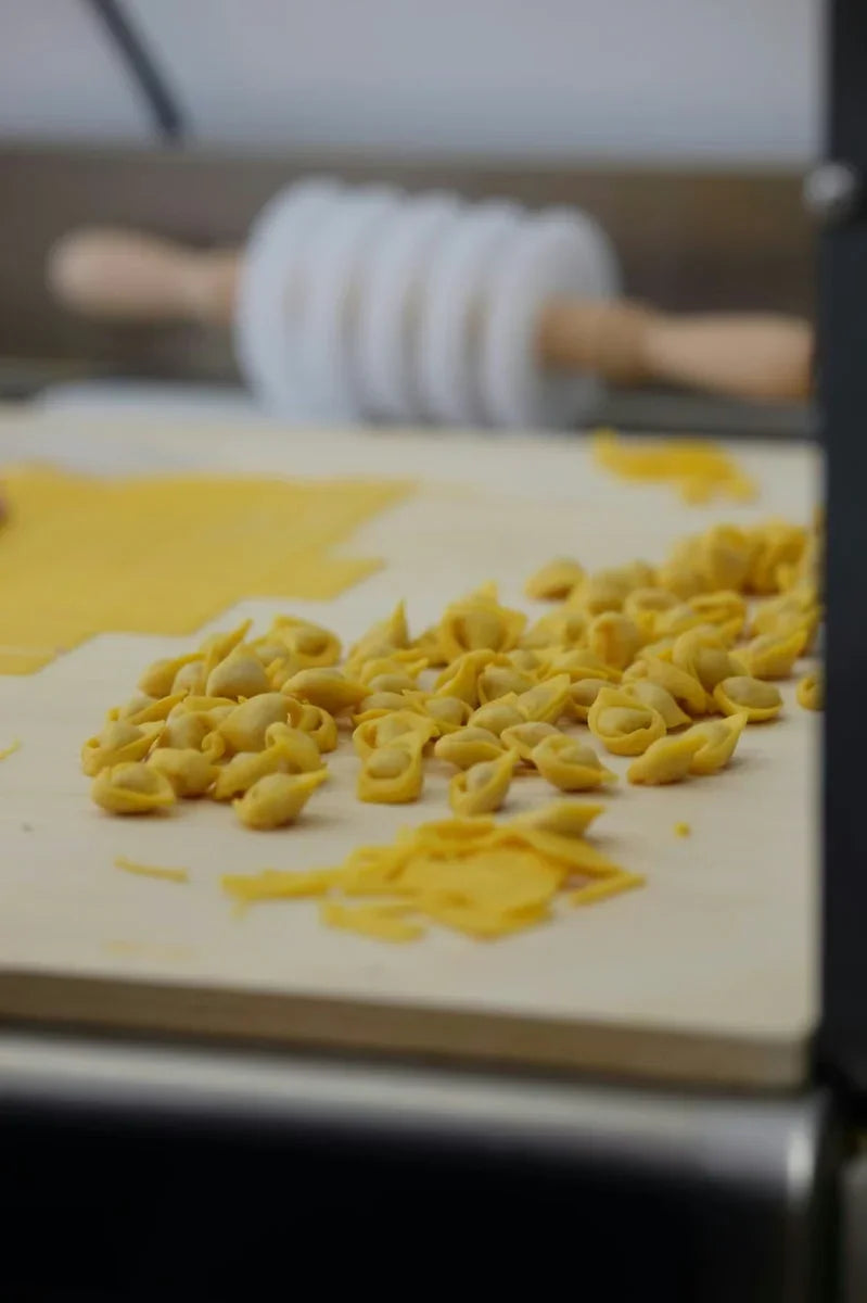Tortellini artigianali freschi su tagliere di legno, pasta emiliana fatta a mano.