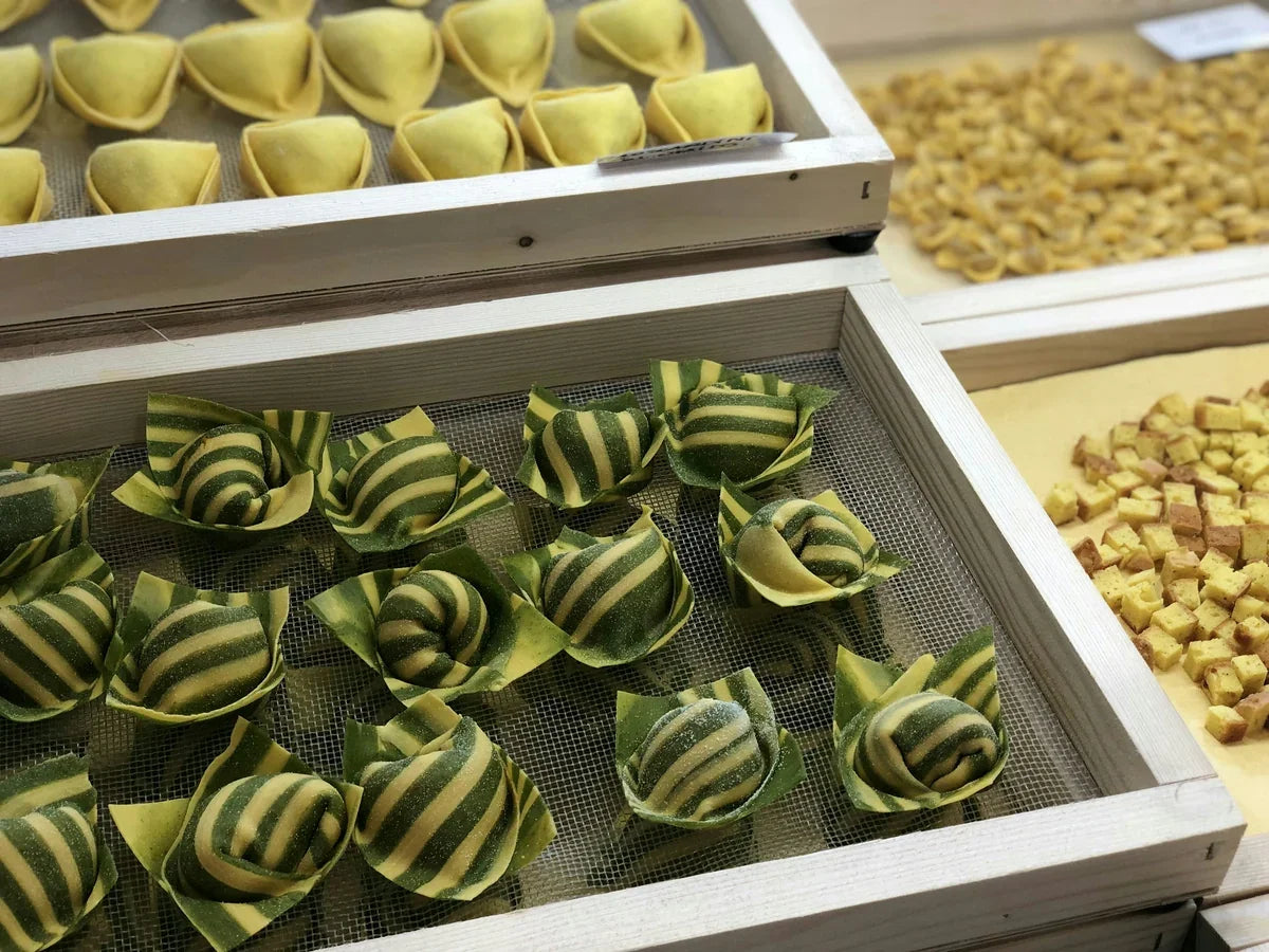 Pasta fresca artigianale emiliana esposta: tortelloni verdi e gialli, cappelletti e cubetti