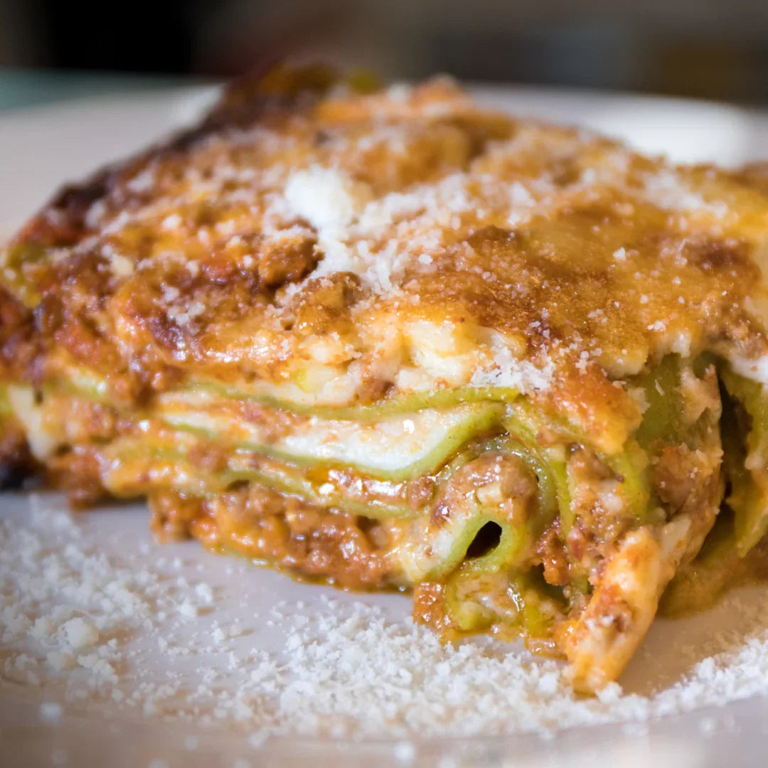 Fetta di lasagna emiliana fatta a mano con ragù e parmigiano, su piatto bianco